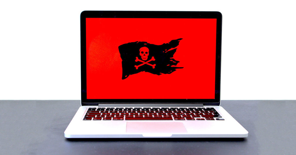Laptop computer with the skull and crossbones flag on a red background.